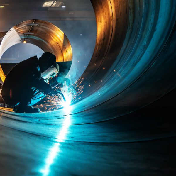 The welder is welding steel plates Welder working inside large metal pipe.