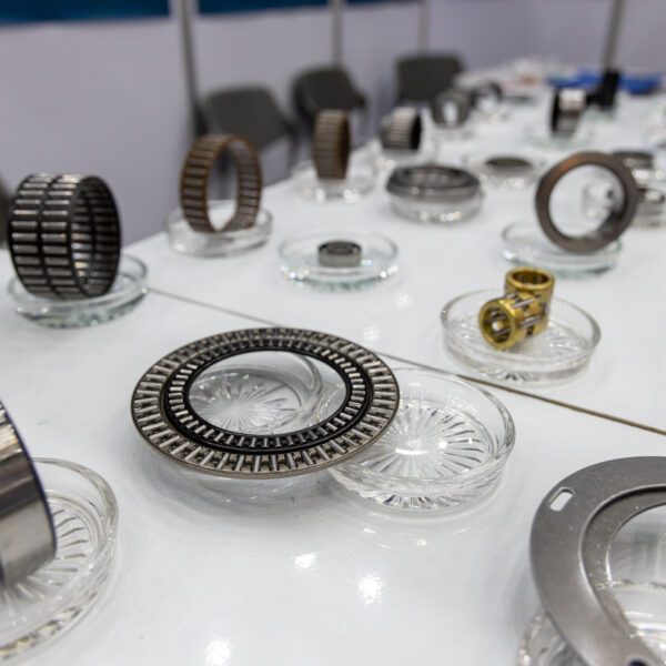 Thrust Needle Roller Bearing displayed on a white table, Roller Bearing, Needle Bearing. Assorted precision industrial bearings on display.