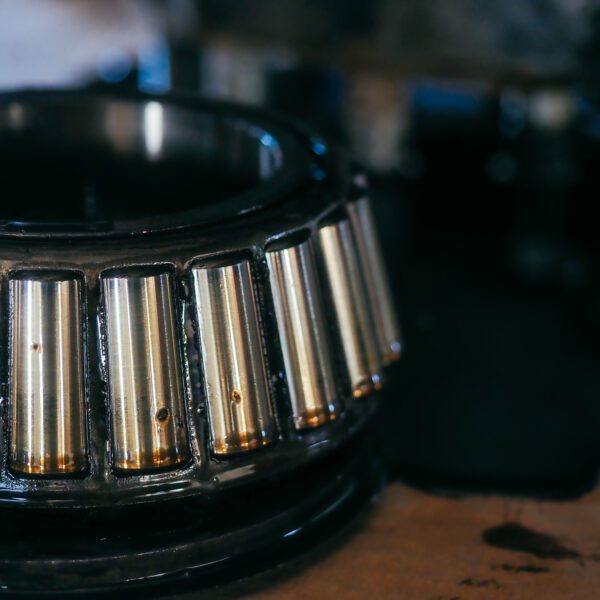Close-up of a tapered roller bearing in grease on a dark industrial background background. A spare part of the mechanism of a truck or tractor. Large industrial roller bearing with oil.