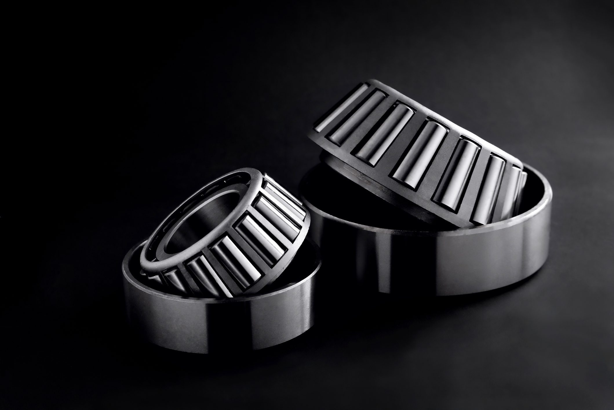 roller bearings on a black background, blank for creativity. Parts for machines and mechanisms in rotation units. selective focus copy space Three cylindrical roller bearings.