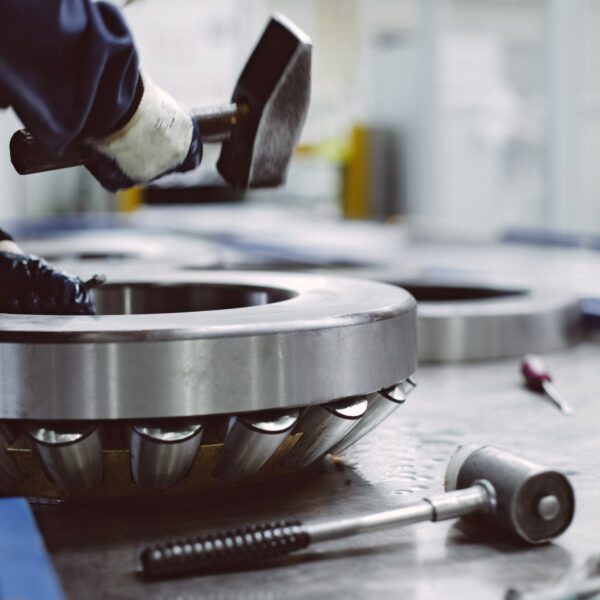Industrial barrel bearing assembly and service Worker hammering large industrial bearing.